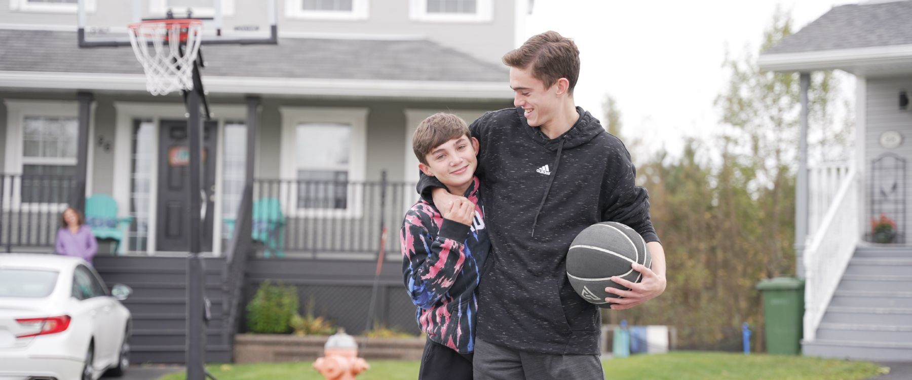 Ryan et Kyle Miller sourient en jouant au basket devant leur maison familiale.